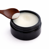 Black jar of cream with a wooden spoon on a white background