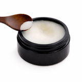 Black jar of cream with a wooden spoon on a white background