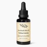 Black bottle of Snowbrush Skin Oil with a beige label on a white background