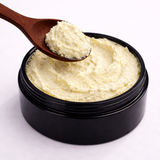 Black container of white cream (Sun Blocker: Natural Sun Screen) with a wooden spoon